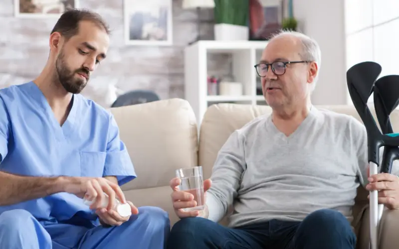 Infirmier à domicile préparant et donnant des médicaments à un senior pour sécuriser son traitement